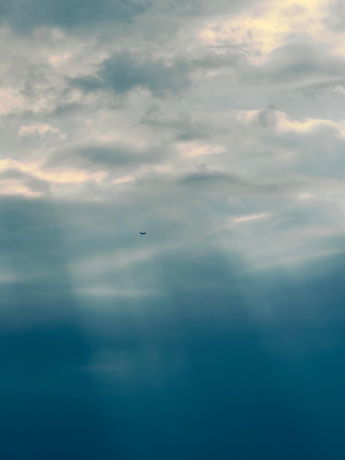 A small plane crossing a layered cloudy sky
