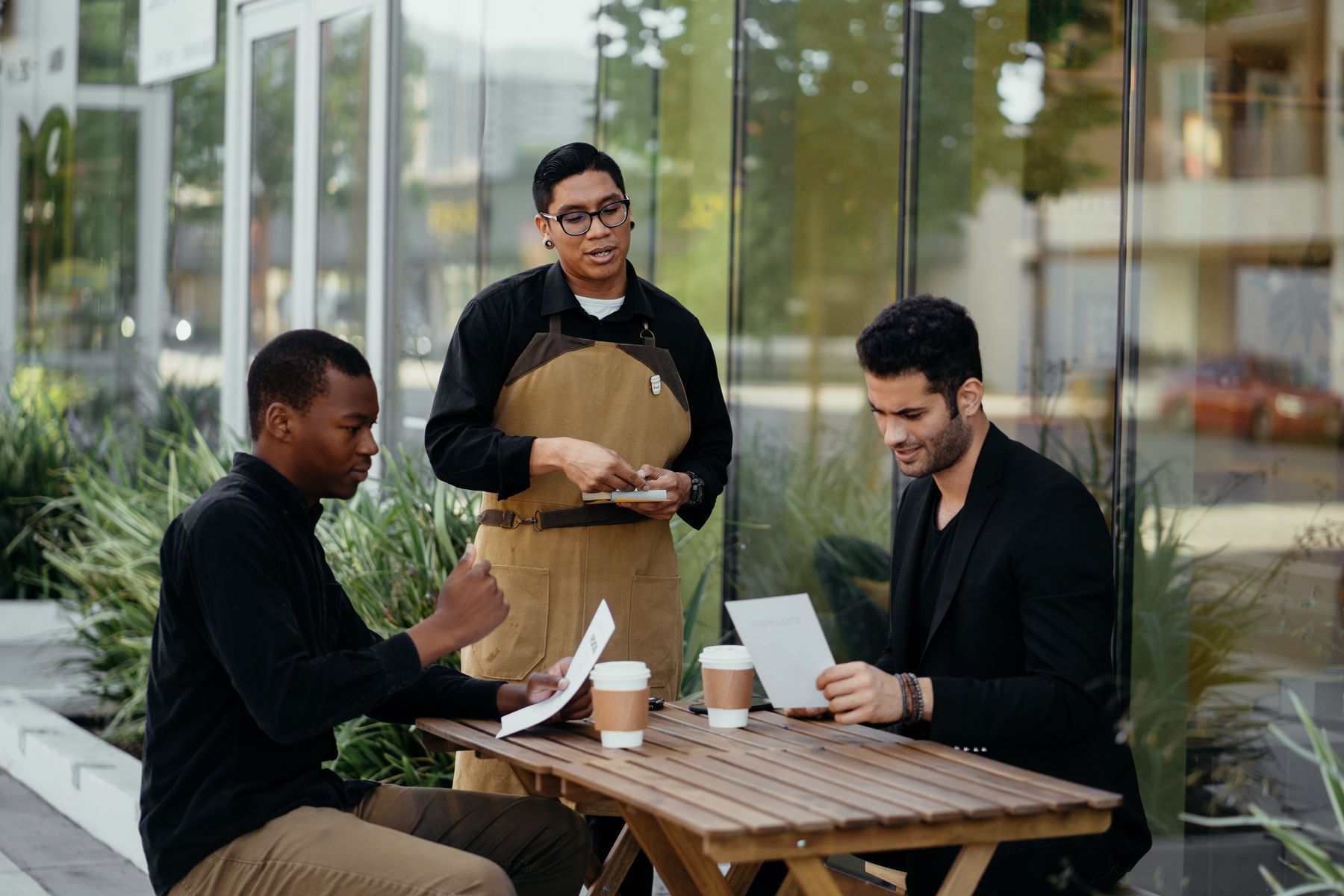 Customers reviewing a menu with a waiter at a restaurant table
